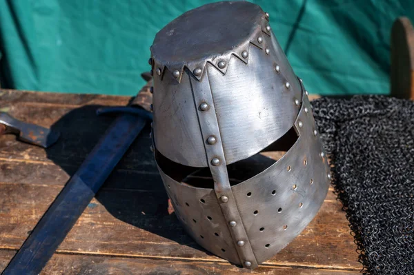 Ortaçağ şövalye miğferi ve kılıcı ahşap masada.