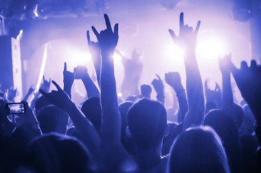 Parlak sahne ışıkları önünde konser kalabalığının siluetleri