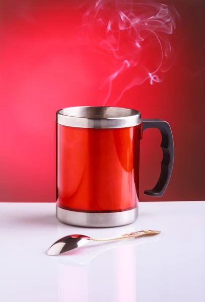 Red travel mug with hot tea and spoon