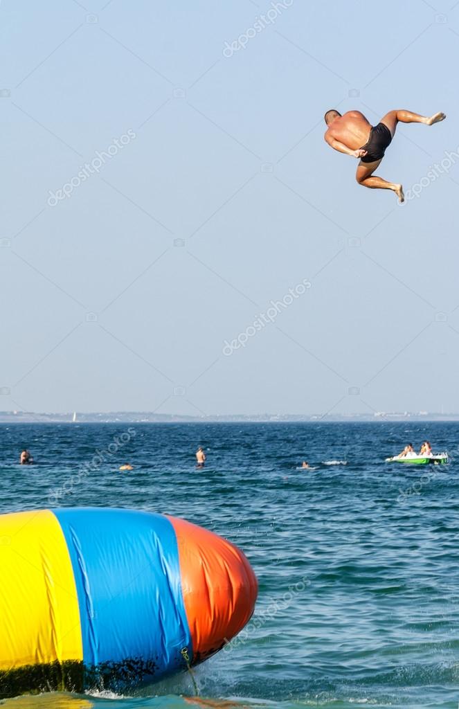 Young man is jumping with inflatable water catapult baloon Stock Photo by  ©ancher 30232739