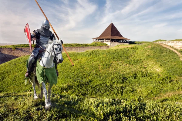 Gepanzerter Ritter auf Haudegen über alter mittelalterlicher Burg — Stockfoto