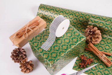 Noel hediyesi paketleniyor, süslemeler ve ambalaj kağıdı görünür.