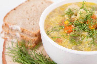 Dereotuyla süslenmiş sebze ve tavuk çorbası, taze ekmekle servis edilir.