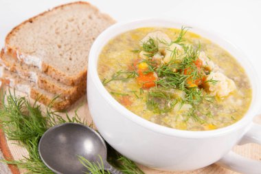 Dereotuyla süslenmiş sebze ve tavuk çorbası, taze ekmekle servis edilir.