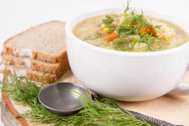 Dereotuyla süslenmiş sebze ve tavuk çorbası, taze ekmekle servis edilir.