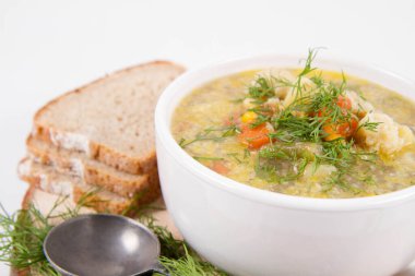 Dereotuyla süslenmiş sebze ve tavuk çorbası, taze ekmekle servis edilir.