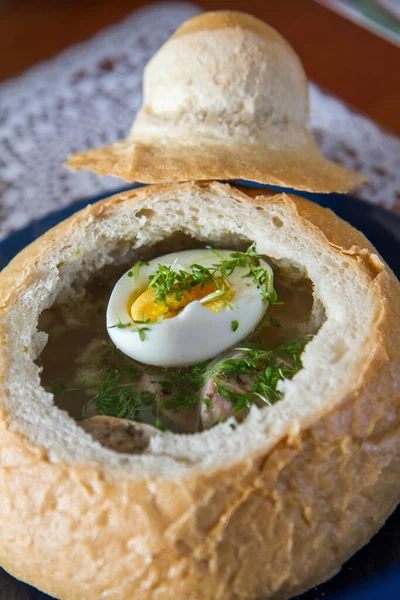 Sour barley soup served in hollowed bread with egg, watercress