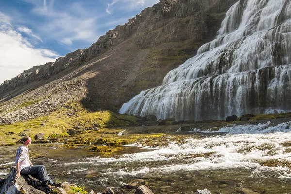 Mujeres jóvenes en piedra en el fondo Cascada de Dynjandi . — Foto de Stock