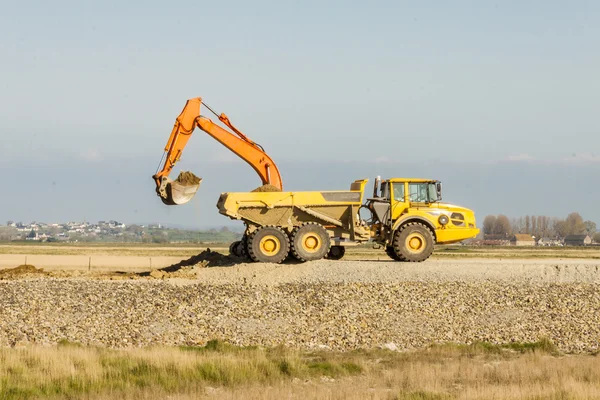 Gelber Bagger belädt Erde auf einem LKW im Bergwerk. — Stockfoto