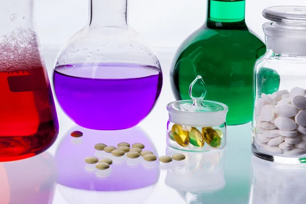 Laboratory glassware with liquids of different colors and tablet Stock Image