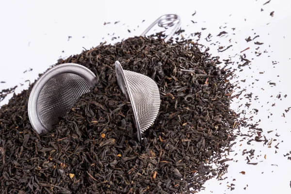 Black tea and tea strainer on white background. — Stock Photo, Image