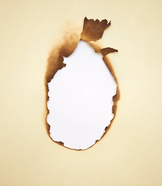 Burned hole within yellow paper. Grunge frame with scorched edge — Stock Photo, Image