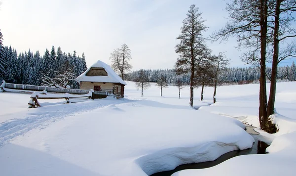 País invernal con casa de campo, arroyo, madera y llano cubierto de nieve país — Foto de Stock