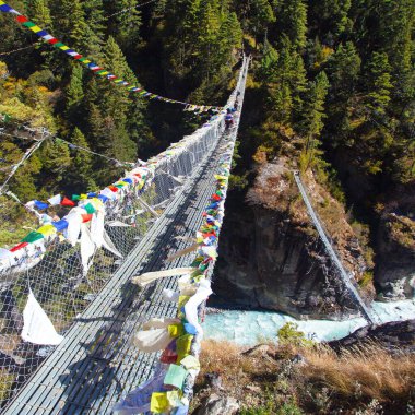 Dudh Koshi Nadi nehrinin üzerindeki Namche Çarşısı 'nın altında Nepal Himalayalar' da dua bayraklarıyla asılı iki halat asma köprüsü Everest ana kampı yürüyüşü.