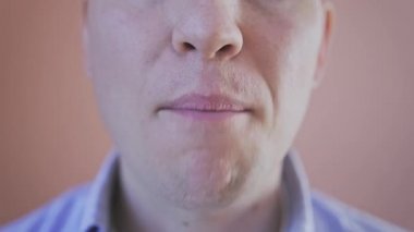 Genç beyaz bir adam konuşurken dudaklarını oynatıyor. 