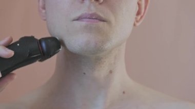 Çenesini tıraş eden genç bir adamın önü..