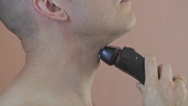 Side view of part of a young men face who is shaving his chin. — стоковое видео