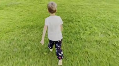 Mutlu küçük çocuk parktaki yeşil çimlerde koşuyor. Kaçan bir bebeğin yüz portresi yok. Nesnenin elde taşınan yüksek kaliteli 4K görüntüsü takip ediliyor.