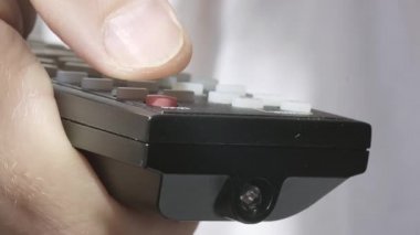 Kafkasyalı bir erkeğin televizyon kumandasını tutarken ve akıllı televizyonu açarken ya da kapatırken ön görüntüsü. Televizyonu açıp evde dinlenme kavramı. Süper makro yüksek kalite 4K görüntü.