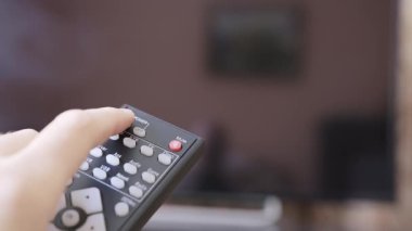Kafkas erkek eli televizyonun uzaktan kumandasını tutuyor ve akıllı televizyonu açıyor. Televizyonu açıp evde dinlenme kavramı. Süper makro yüksek kalite 4K görüntü.