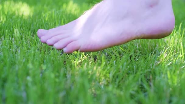 若い白人男性の足は 晴れた日に緑の芝生の短い草の上を歩いている間に ゆっくりとフレームに入ってきています 低い角度だ クローズアップはまだ高品質4K映像 — ストック動画