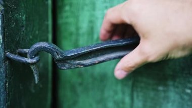 Kafkasyalı bir adamın eli, kancaya takılmış bir evin ahşap kapısını açar. Ahşap kapı yeşile boyanmış. Karanlık kapı. İlkel kapı kilidi. Yüksek kalite 4k görüntü