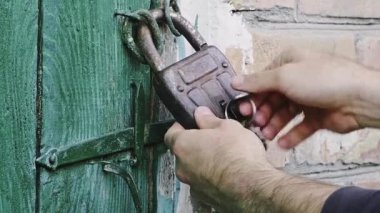 Kafkasyalı bir adamın elini açtığında yeşil ahşap kapıya asma kilit takılır. Yanlamasına hareket eden dolly yüksek kalite slayt 4k görüntü 