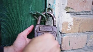 Kafkasyalı bir adamın elini açtığında yeşil ahşap kapıya asma kilit takılır. Sabit kaliteli slayt 4K görüntü 