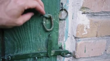 Beyaz bir adamın eli, yeşil ahşap kapıya asılı olan eski bir asma kilidi kapatır. Sabit kaliteli slayt 4K görüntü 