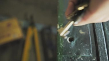Kafkasyalı bir adamın anahtar deliğine anahtarlarını yerleştirip kapının önünde asılı bırakması. 4K 'lık yüksek kaliteli slayt görüntüsü. 