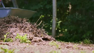 Man with wheelbarrow is getting ready for the work in the garden by sticking the pitchfork in the ground. Concept of starting a new task. High quality 4k footage