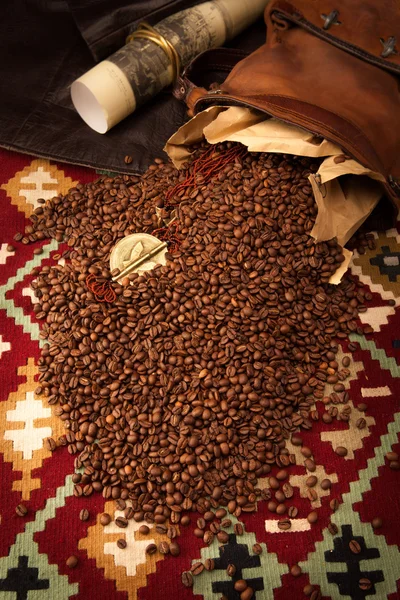 Spilled coffee beans and African medallion with eagle — Stock Photo, Image