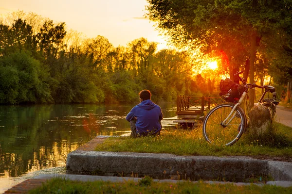 Embankment en Treviso, Italia, el chico solo relajarse y disfrutar de la puesta de sol — Foto de Stock