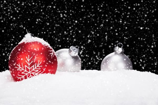 Röd och silver julgranskulor i snö — Stockfoto