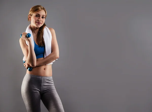 Smiling fitness woman with a white towel and dumbbells — Stock Photo, Image