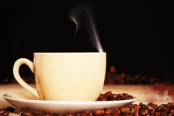 Copo de café fumegante com grãos de café em um tecido de juta — Fotografia de Stock