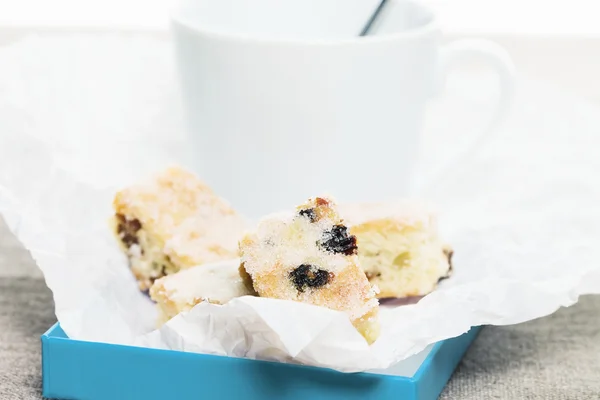 Small stollen cakes in parchment paper in front of a white cup — Stock Photo, Image