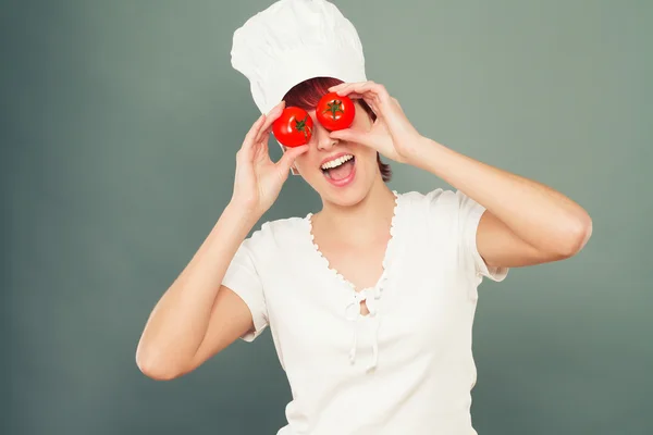 Female cook holding tomatoes on her eyes — Stock Photo, Image