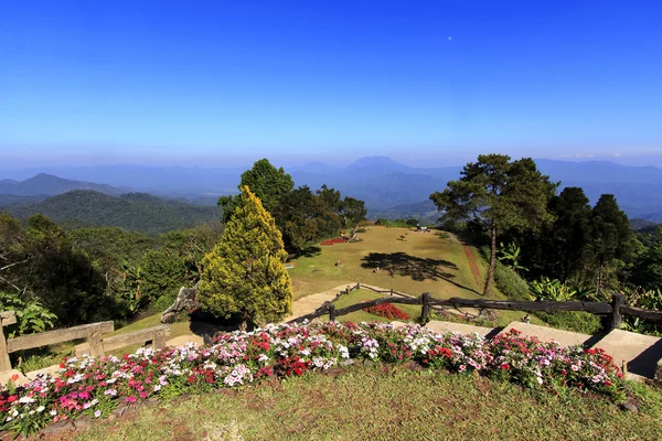 Villaggio di montagna con giardino fiorito in cielo blu brillante — Foto Stock