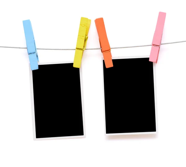 Colorido clothespin pendurar papel fotográfico em branco no fundo branco — Fotografia de Stock