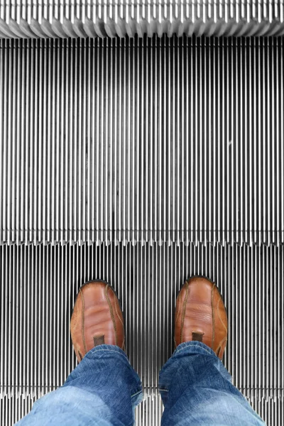 Man with pair of leather shoes standing on move up escalator — Stock Photo, Image