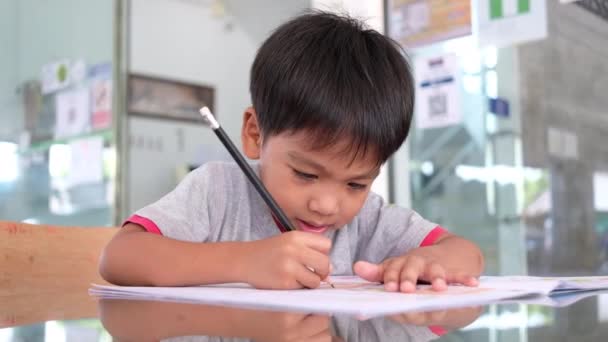 Asiático pequeño chico haciendo tarea en casa — Vídeo de stock
