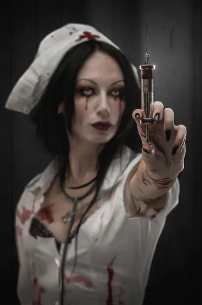 Terrible nurse with a syringe with blood in hand — Stock Photo, Image