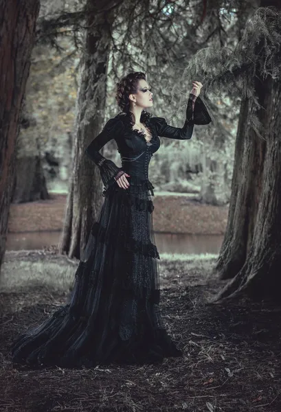 mujer en bosque en vestido negro