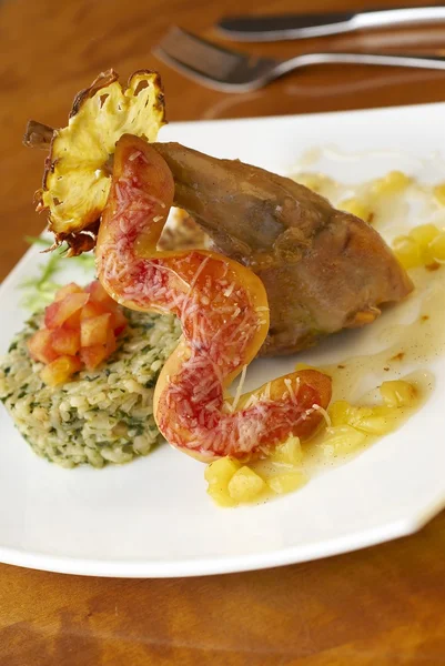 Rabbit leg with green risotto, pineapple sauce and bread sausage — Stock Photo, Image
