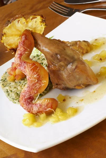 Rabbit leg with green risotto, pineapple sauce and bread sausage — Stock Photo, Image