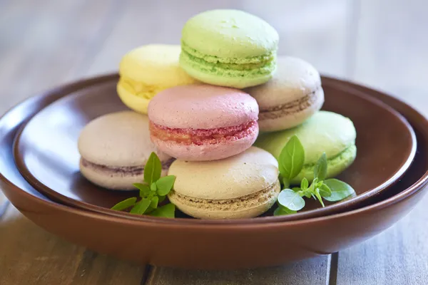 Kahverengi plaka üzerinde renkli macaroons — Stok fotoğraf