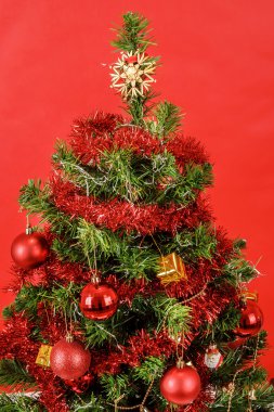 Kırmızı arka planda süslenmiş Noel ağacı