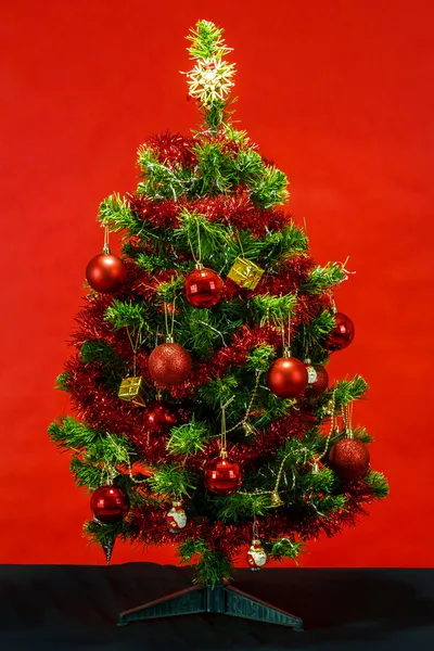 Διακοσμημένο χριστουγεννιάτικο δέντρο σε κόκκινο φόντο — Φωτογραφία Αρχείου