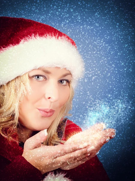 Alegre bonita mujer soplando estrellas en rojo sombrero de Santa Claus — Foto de Stock